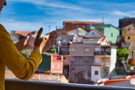 Young woman clapping her hands on the balcony showing gratitude to all the healthcare workers during the coronavirus outbreakの写真素材