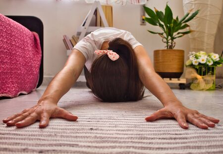 Young woman in her living room doing yoga and meditation in sport fashion.