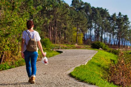 Girl pick up her trash and walk in a hiking trail
