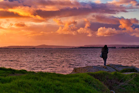 silhouette of a woman walking at sunsetの写真素材