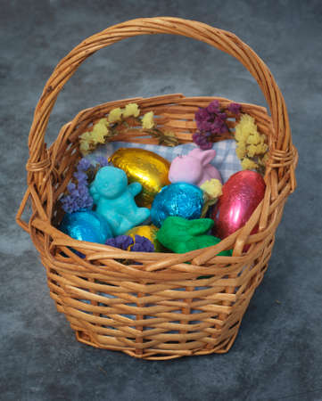 Basket with easter eggs in colored tin foil, bunnies and flowers.