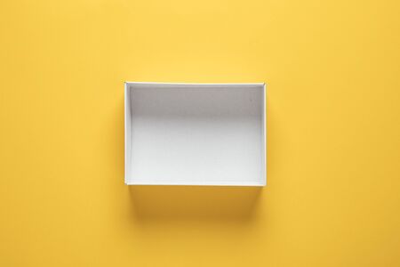Empty brown cardboard box on yellow background. Empty delivery box, flat layの写真素材