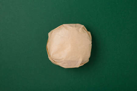 Packed burger on green background, top view. Wrapped hamburger sandwich, blank mock up