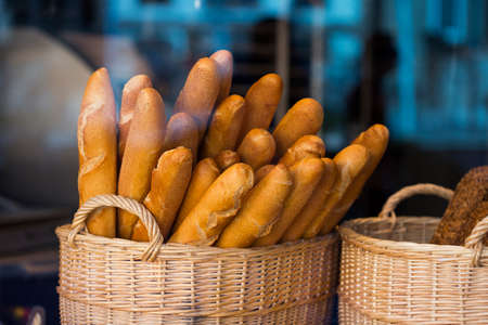 Wicker basket full of baguettes, tasty delicious crusty bread in bakery shopfrontの写真素材