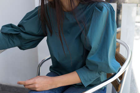 Close up fashion detail, young woman wearing a dark teal puff sleeve blouse