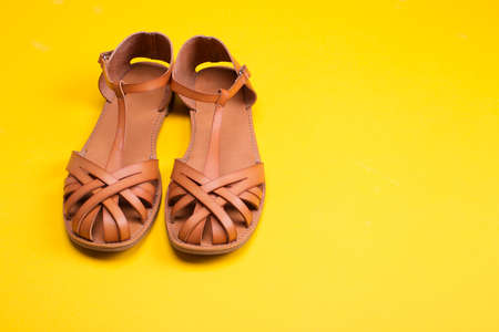 Leather sandals on yellow background. Woman casual summer vacation outfit, flat sole sandalsの写真素材