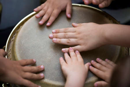Children playing together at djembe drum, close up. Beating the djembeの写真素材