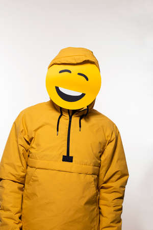 Guy with funny emoji mask and hoodie, big grin smiling face, man having a good timeの写真素材