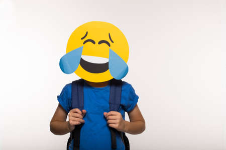 Young boy with funny paper emoji mask, back to school. Happy child with laughing faceの写真素材