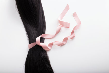Binding hair with pink satin ribbon. Hair donation, cancer awarenessの写真素材