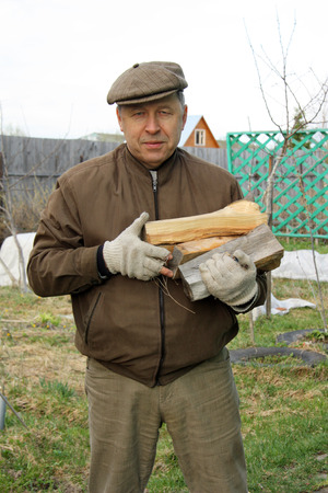 Senior country man carrying firewoodの写真素材