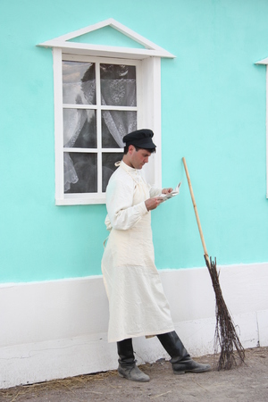 RUSSIA, MOSCOW, TIMES AND AGES FESTIVAL, 8 JUNE 2014 - Vintage man janitor reading news in a yard