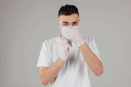 Man in white T-shirt wearing a mouth protection medical mask to prevent getting sick at work or on...