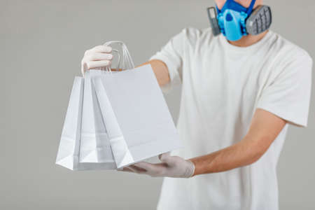 Delivery man holding paper bag with food on white background, food delivery man in protective mask...
