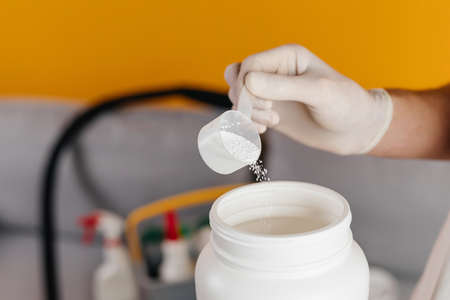 Man wearing mask and gloves, using detergent for making cleaning at home.の写真素材