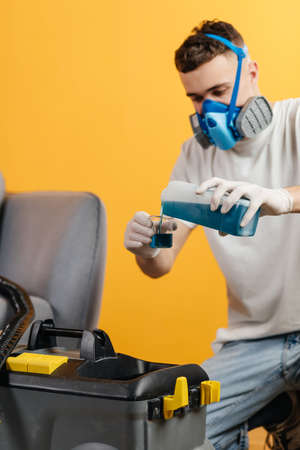 Dry cleaners employee, wearing mask and start removing dirt from furniture in flat. Professional...