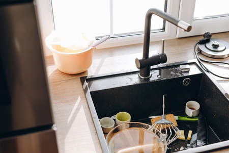 Pile of dirty dishes in the metal sink.の写真素材