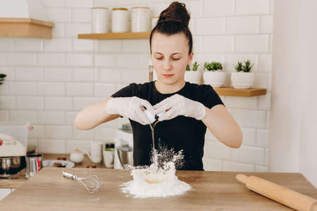 Baker s hands with plain flour well and eggs in preparation process for baking, cooking, pastry making. Woman breaks eggs in flour. Adding egg yolk to cooking.の写真素材