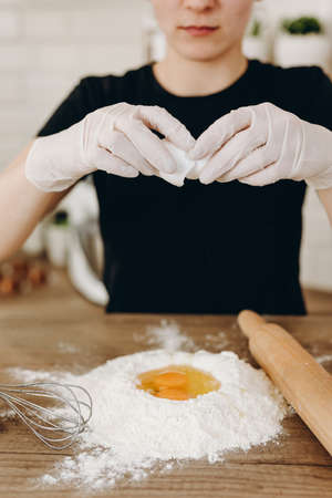 Baker s hands with plain flour well and eggs in preparation process for baking, cooking, pastry...