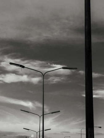 electric poles standing against sky in black and whiteの写真素材