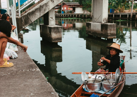 Damnoen Saduak, Thailand-August 9, 2009: People sells souvenirs from his boat at a floating market near Bangkokのeditorial素材