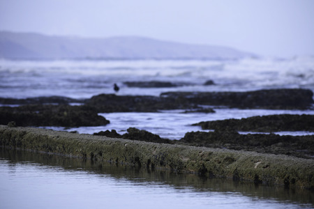 Calm Water In A Manmade Tide Pool With Rocks And Waves Defocused Backgroundの写真素材