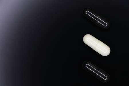 Black And White Gel Pill Capsules On Smooth Blackの写真素材