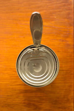 Open canned meat and fork on a wooden table.の写真素材