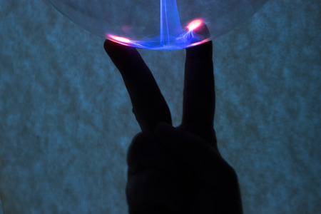 In the background is the hand that was illuminated by plasma from plasma lamp.の写真素材