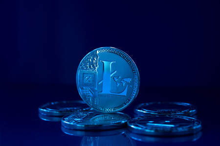 On a blue glass background are coins of a digital crypto currency Litecoin. On the glass background is a reflection of coins.の写真素材