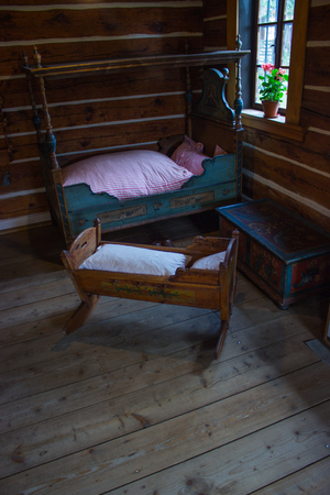 Retro room with bed and cradle with blanket, clogs and chest.の写真素材