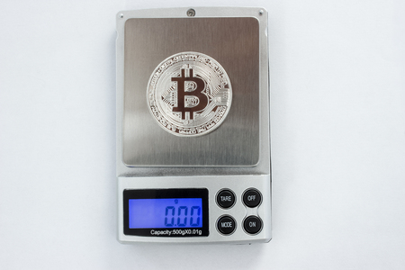 Bitcoin on the digital scales on the white background.の写真素材