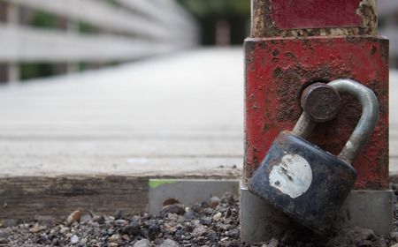 With a lock pad locked across the bridge. Padlock detail. In the background are trees.の写真素材