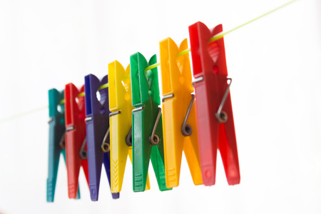 Colorful clothespins hanging on a clothesline. The background is white.