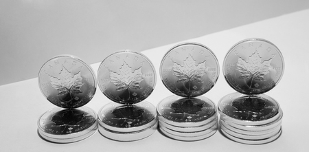 On a gray background are silver maple leaves coins of silver investment from Canadian Mint.の写真素材