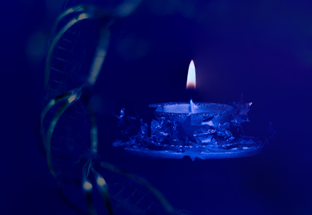 Candle on blue background. In the foreground is the Christmas adornment.の写真素材