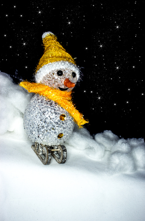 Snowman on sledge in snow in the black background sky dotted with stars.の写真素材