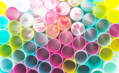 Many colorful straws stacked on top of each other. Beyond the straw penetrates the white light...