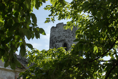 View of castle tower over branches of trees. In the background is blue sky with white clouds.の写真素材