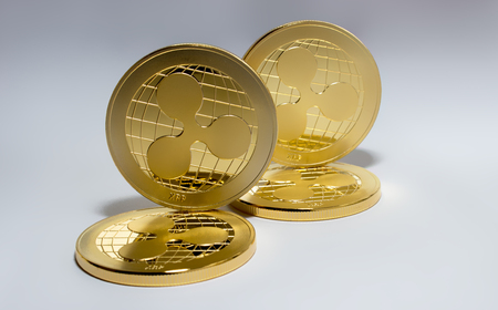 On the white background are gold coins of a digital virtual crypto currency - ripple. In addition to the lying coins, there is a standing ripple.の写真素材