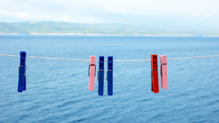 Clothespins hanging on the clothesline. In the background is the sea with waves from the wind and...