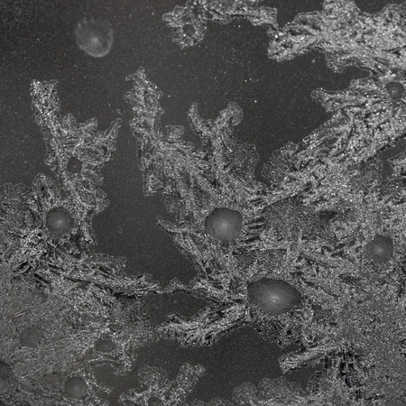 Black background with silver frost on the window. Frozen water on the window creates silver...