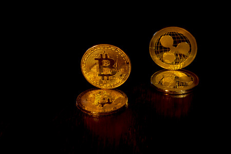 Gold crypto curencies coins bitcoin and ripple on a black background. In addition to the lying coins, there are standing coins.の写真素材