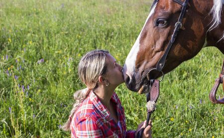 A young girl looks at horse and kissing her horseの写真素材