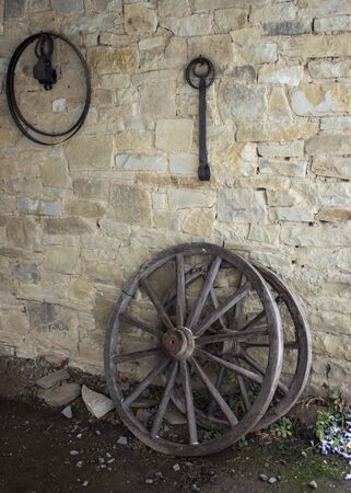 Old wooden wheels on a carriage leaning against a wallの写真素材