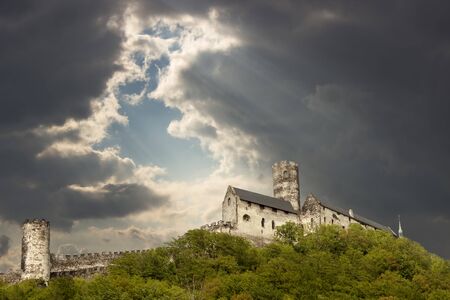 Panoramic view of Bezdez castle  with big tower in the Czech Republic. In the foreground there are trees, in the background is a hill with castle and clouds are gathering.の写真素材