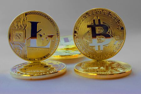 On a gray background are gold coins of a digital crypto  currency - litecoin and bitcoin. In addition to the lying coins, there are standing bitcoin and litecoin.の写真素材
