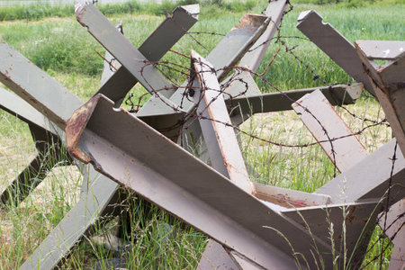 Hedgehod anti-tank barrier with rusty barbed wireの写真素材