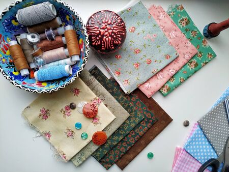 Cotton fabric in different colors and accessories for cutting and sewing. Flat lay.