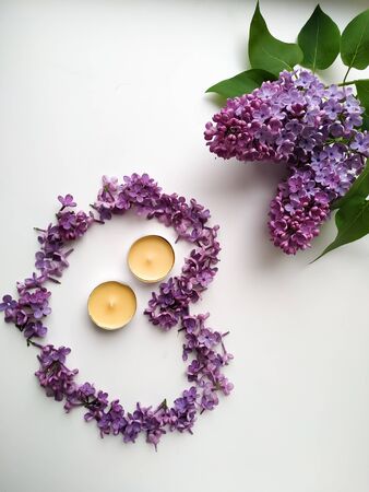 a heart of lilac flowers next to two saffron candles isolated on white background.base for postcardの写真素材